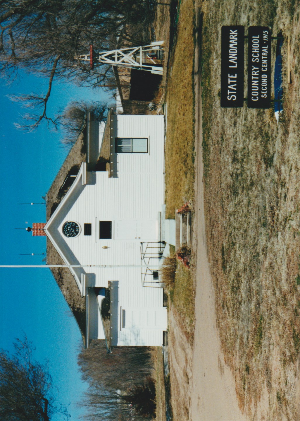 Second Central School, White school house, black and white sign reading Second Central 1915, white and red water well 